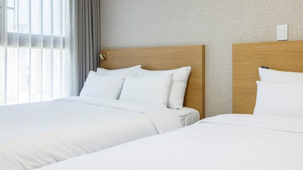 A hotel room with two beds, a wooden headboard, and a textured wall. - Centum Mark Kimstay Yangyang (Yangyang)