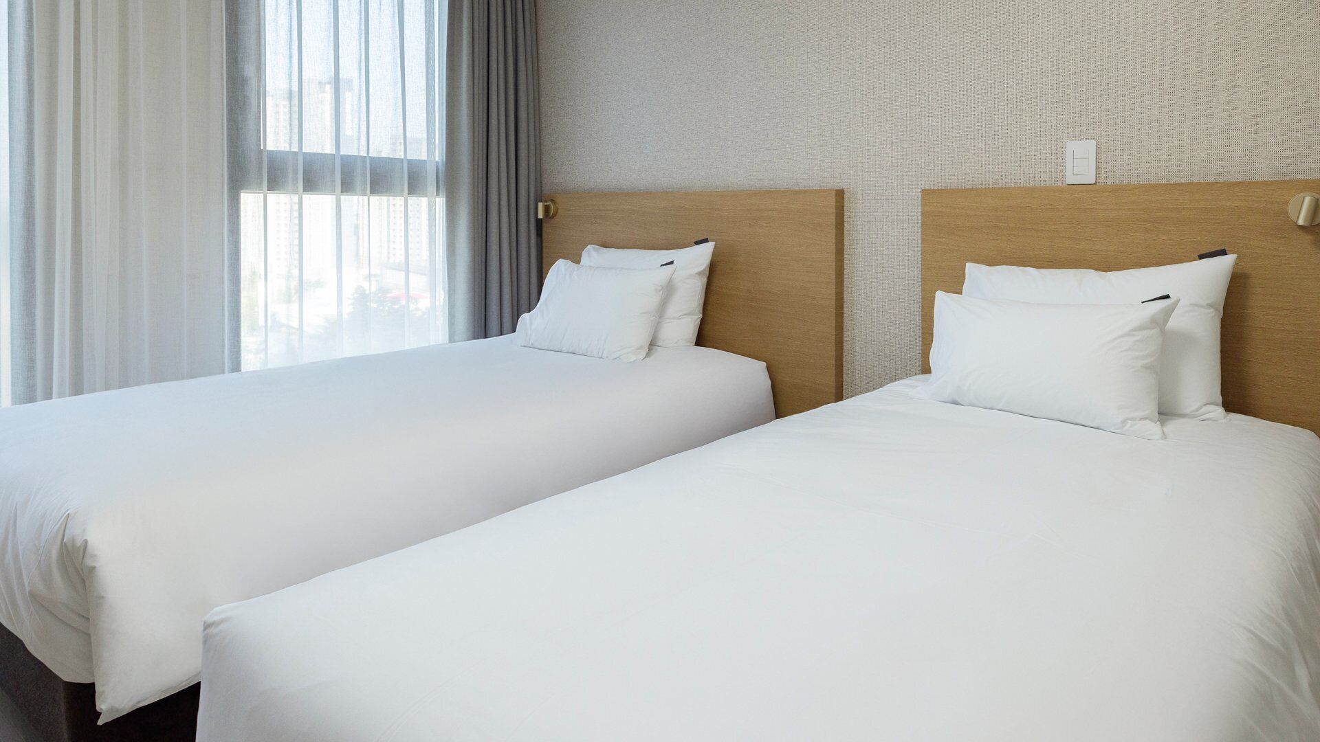 Two single beds with white linens in a hotel room.