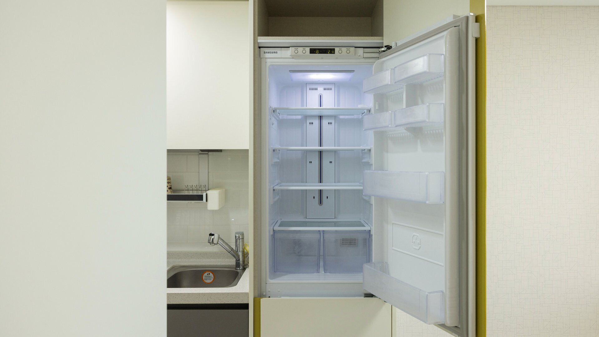 Eine kompakte Küche mit einem eingebauten Samsung-Kühlschrank, einem Spülbecken und einer kleinen Arbeitsfläche.