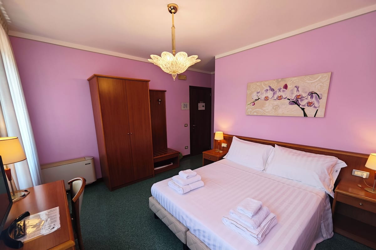 Habitación de hotel con una cama grande, un armario de madera y una pintura de orquídeas.