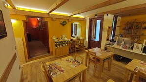 Um quarto aconchegante com pisos e móveis de madeira, um espaço de cozinha com cafeteira e uma prateleira com objetos decorativos.