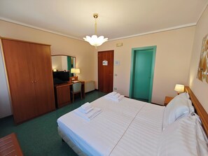 A hotel room with a bed, a desk with a chair, a television, a wardrobe, and a bathroom door. - Casa Malvina (Mira)