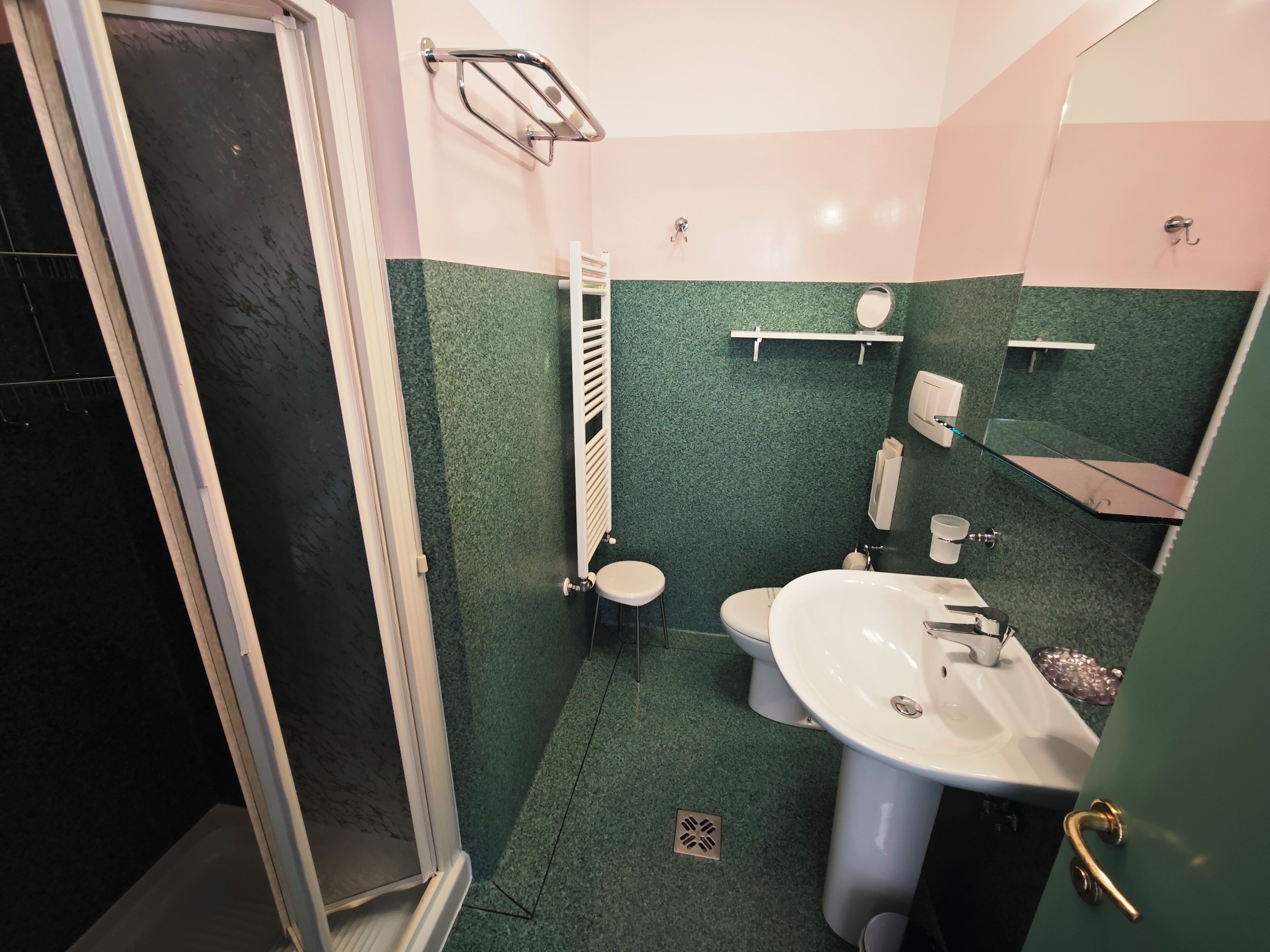 A bathroom with a shower, toilet, sink, and a mirror.