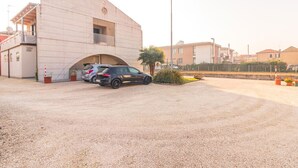 Uma área de estacionamento com dois carros, um edifício com telhado plano e um poste de luz.