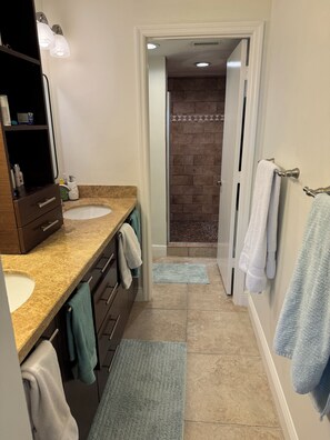 A bathroom with two sinks, a mirror, and a shower area. - Spacious 2/2 Oceanfront Corner Unit with Incredible Direct Beach Views & Access! (Jensen Beach)