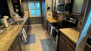 Una cocina moderna con encimeras de granito, electrodomésticos de acero inoxidable y un ventanal que proporciona luz natural.