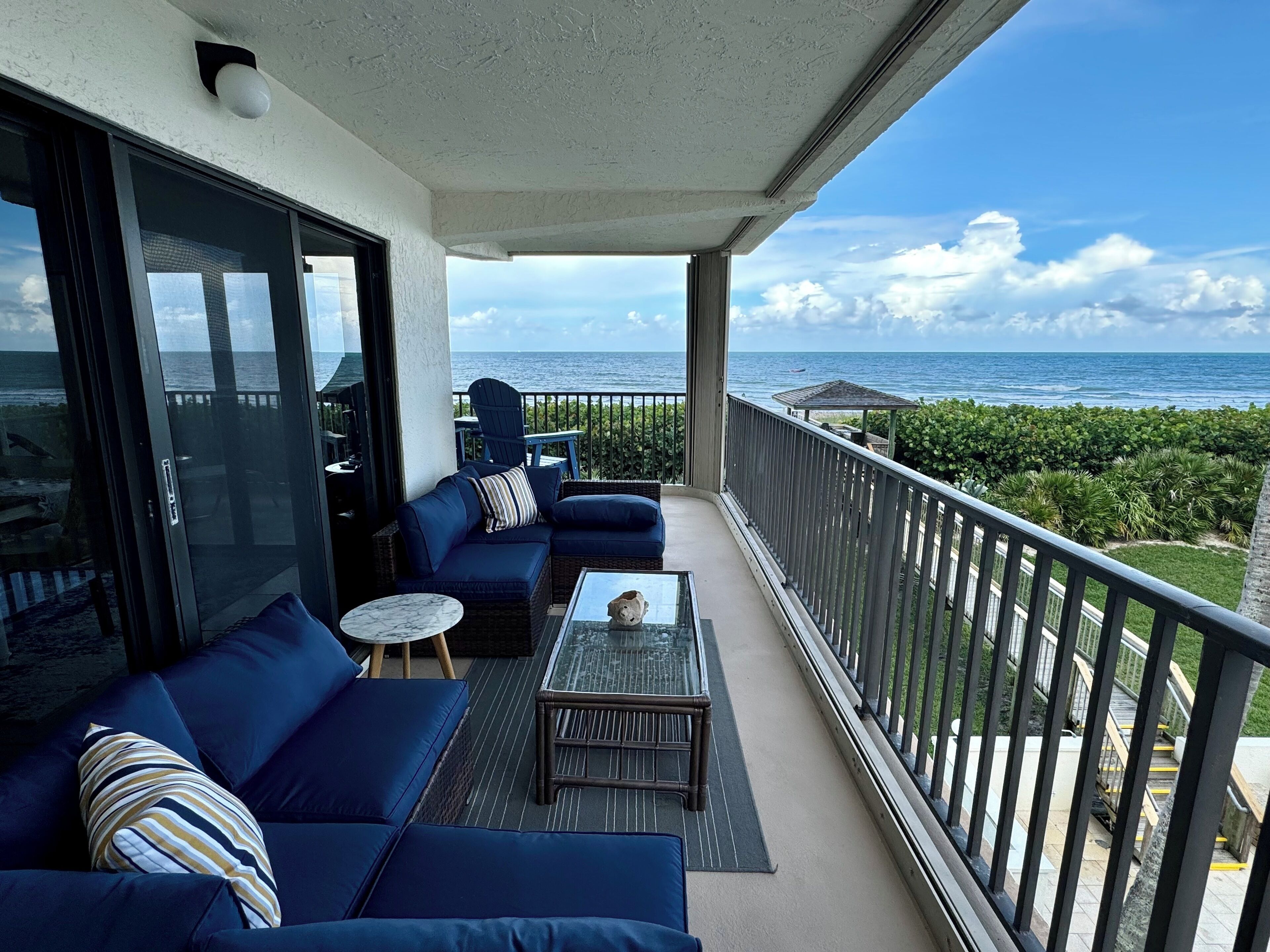 A balcony with a sofa, a small table, and a view of the ocean.