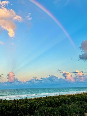 A beach with a clear sky, ocean waves, and a rainbow. - Spacious 2/2 Oceanfront Corner Unit with Incredible Direct Beach Views & Access! (Jensen Beach)
