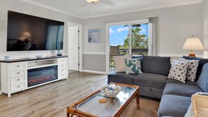 A living room with a flat-screen TV, a fireplace, a sofa, and a ceiling fan.