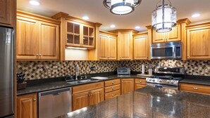 A kitchen with wooden cabinets, a granite countertop, stainless steel appliances, and a patterned backsplash. - Dockside Daze | Lakefront + Hot Tub | Sleeps 12, Stellar Sunsets (Bristol)