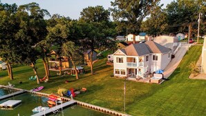 A large house with a dock and boats, surrounded by a well-maintained lawn and trees. - Dockside Daze | Lakefront + Hot Tub | Sleeps 12, Stellar Sunsets (Bristol)