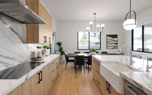 A modern kitchen with marble countertops, wooden cabinets, a central island, and pendant lighting. - Sunrift-Pool & Spa-Game Room-Walk to Old Town! (Scottsdale)