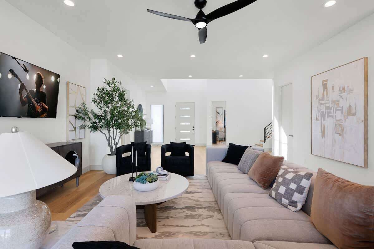 A modern living room with a ceiling fan, a round coffee table, a sofa, and a TV.