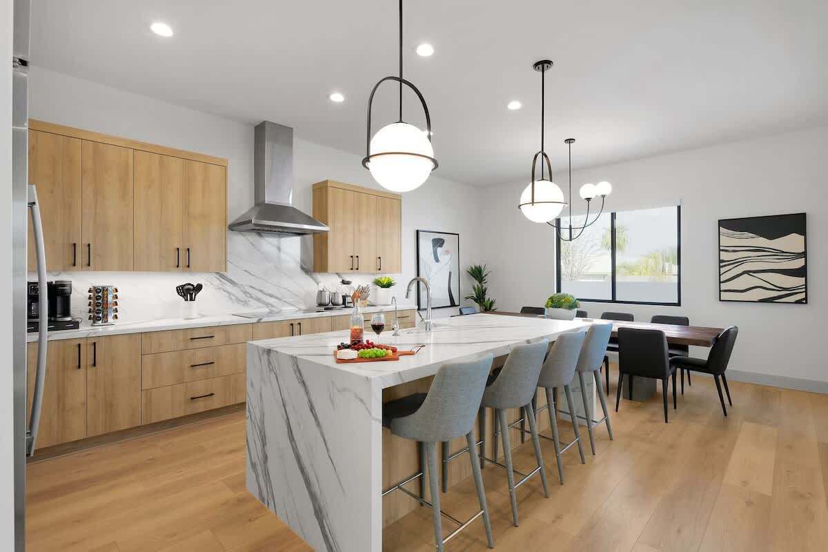 Una cocina moderna con encimeras de mármol, armarios de madera y una isla central con taburetes de bar.