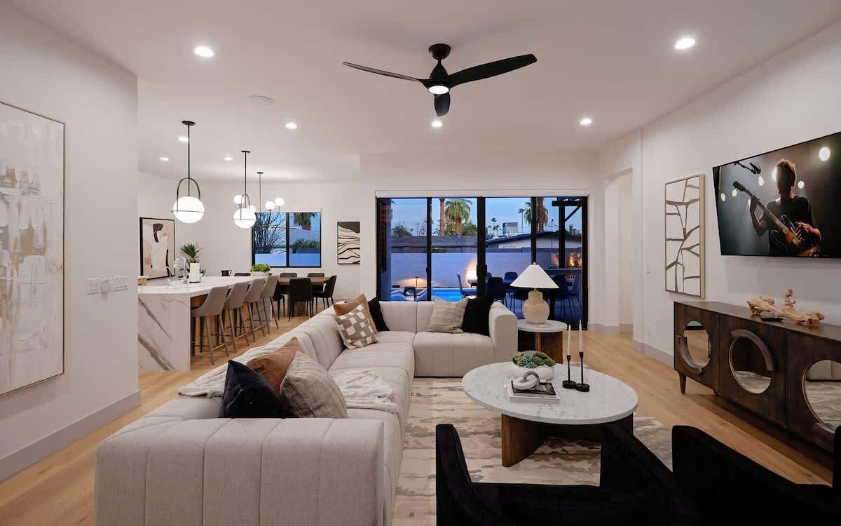 Una sala de estar moderna con sofá, mesa de centro y televisor. Hay un comedor con sillas y una mesa, además de un ventanal con vistas.