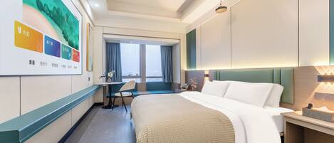 A modern hotel room with a large bed, a desk, and a view of the city.