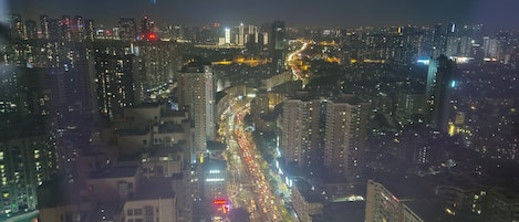Un paisaje urbano nocturno con rascacielos, calles concurrida y letreros iluminados.