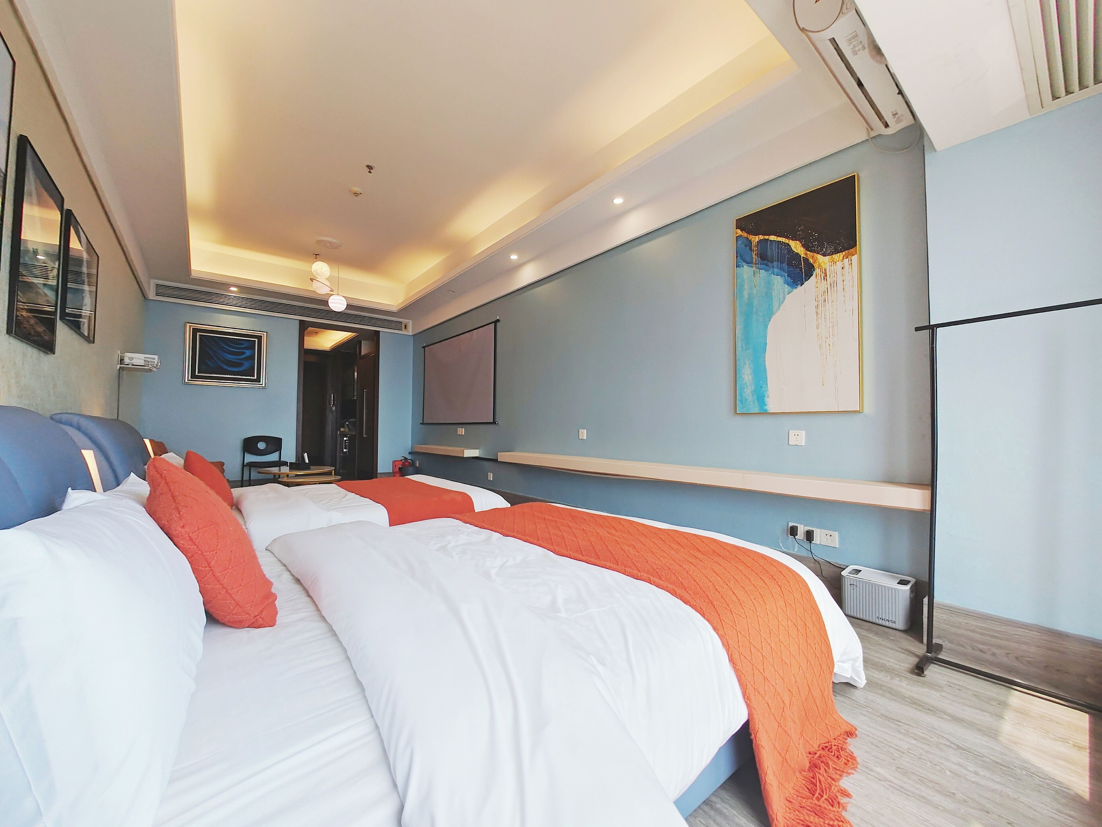 A hotel room with two beds, a TV, and artwork on the walls.