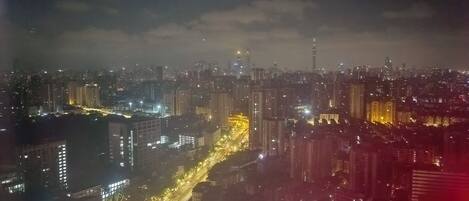 Une vue nocturne d’une ville, avec des bâtiments illuminés et une rue animée.