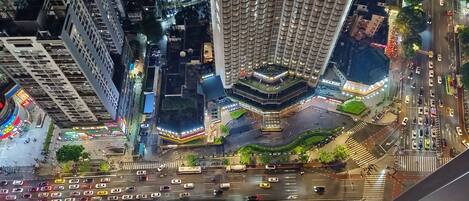 Un edificio de gran altura con un diseño arquitectónico distintivo, un patio central y una intersección con mucho tráfico abajo.