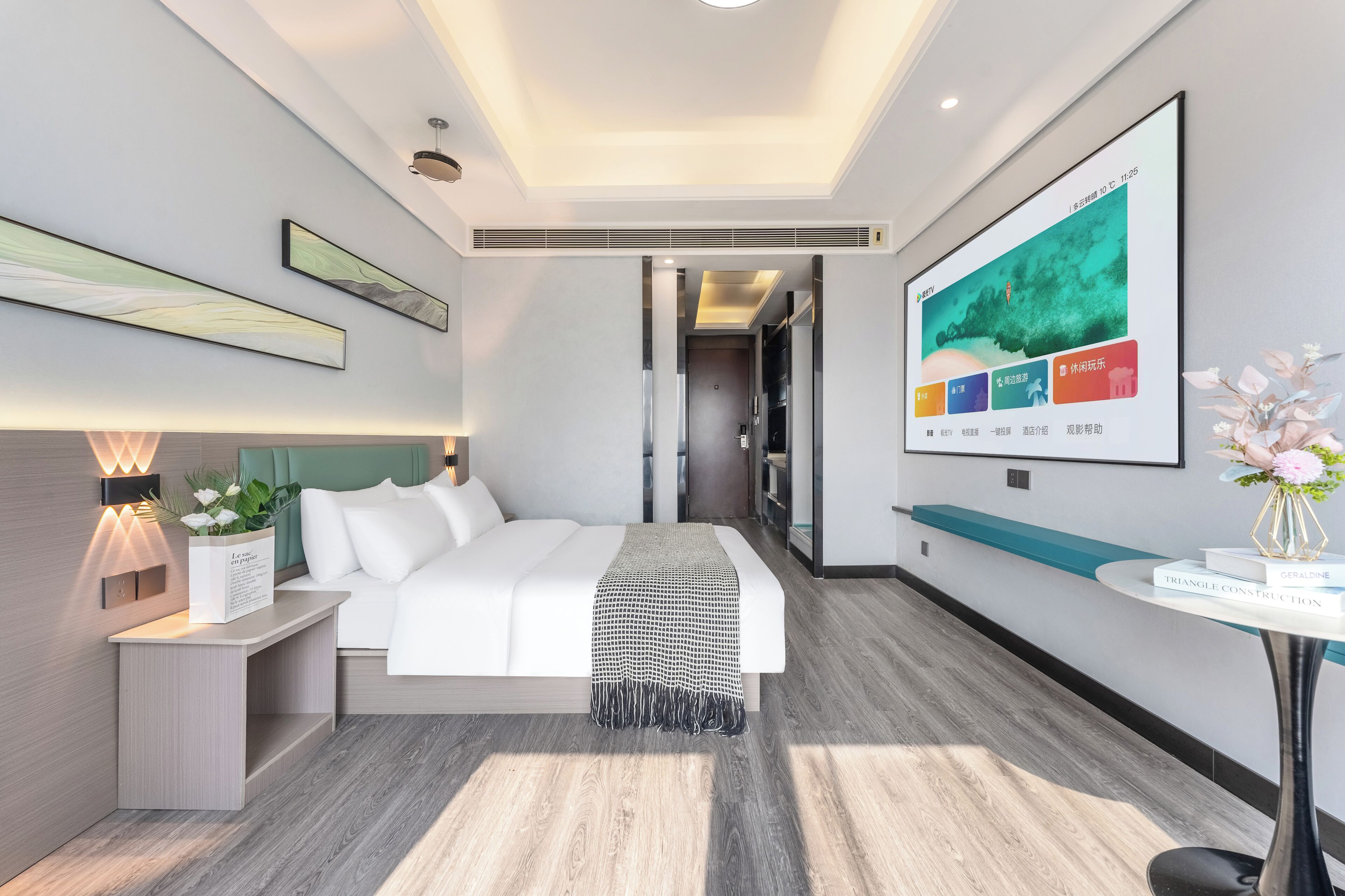 Ein modernes Hotelzimmer mit Bett, Nachttisch und großem Fenster.