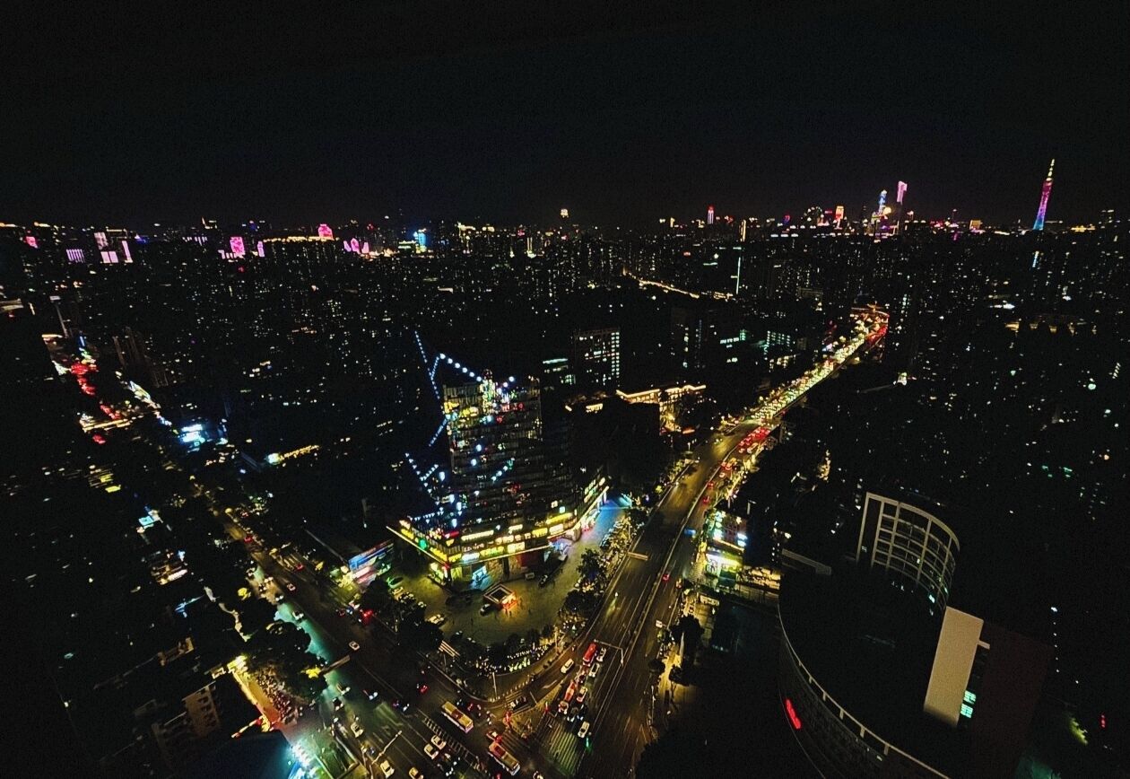 An aerial view of a cityscape at night with illuminated buildings and roads.