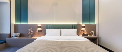 Una habitación de hotel moderna con una cama grande, dos mesitas de noche con lámparas, un taburete y una zona de estar con un banco.