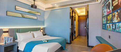 Una habitación de hotel moderna con cama, escritorio con una computadora portátil, mesita de noche y televisión montada en la pared.