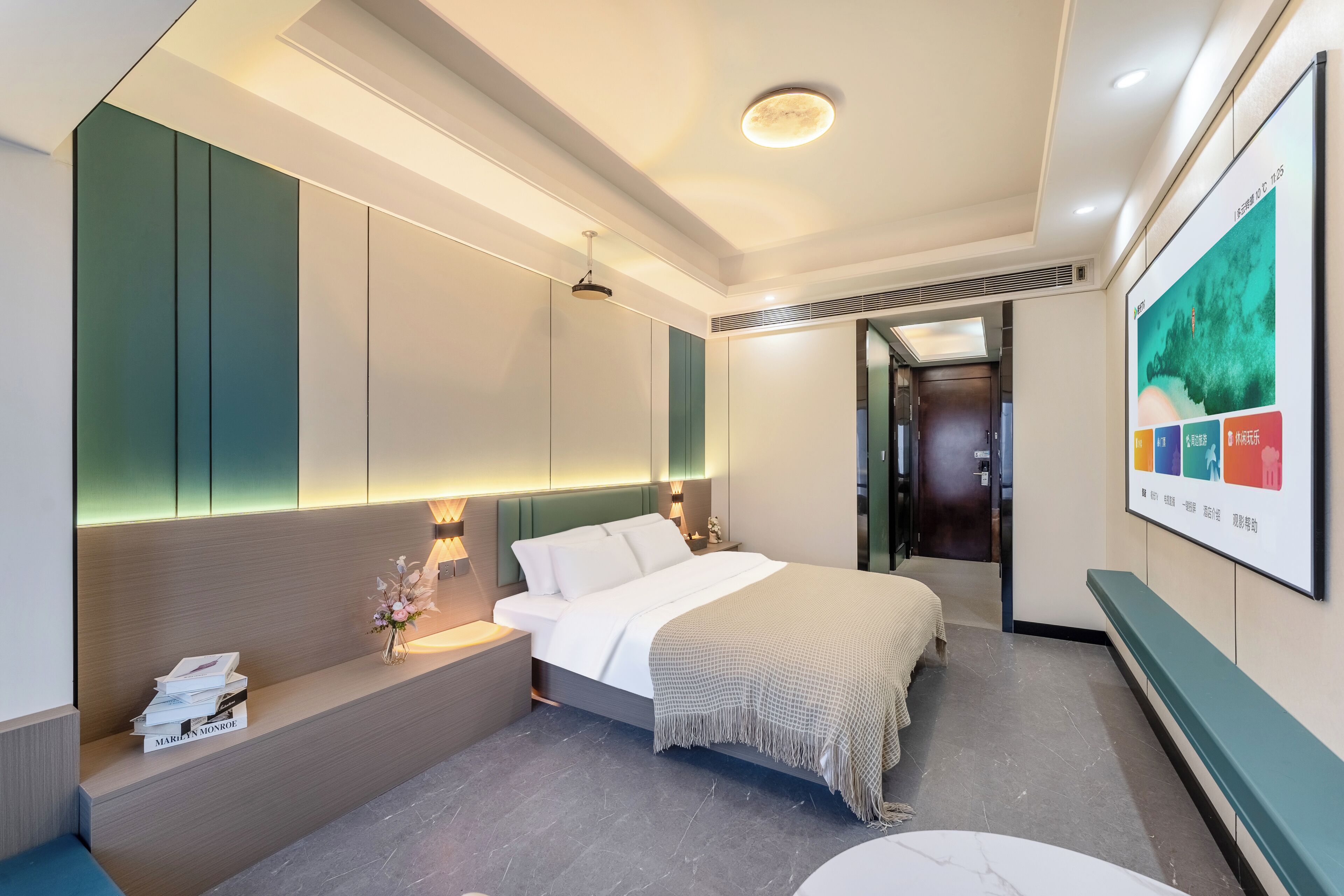 A modern hotel room with a bed, bedside tables, a bench, and a wall-mounted TV.