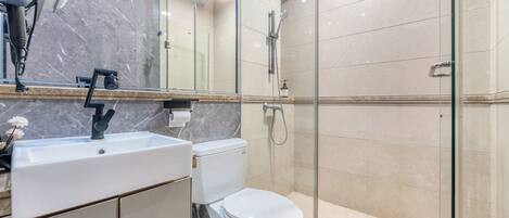 A modern bathroom with a marble sink, toilet, and glass-enclosed shower.
