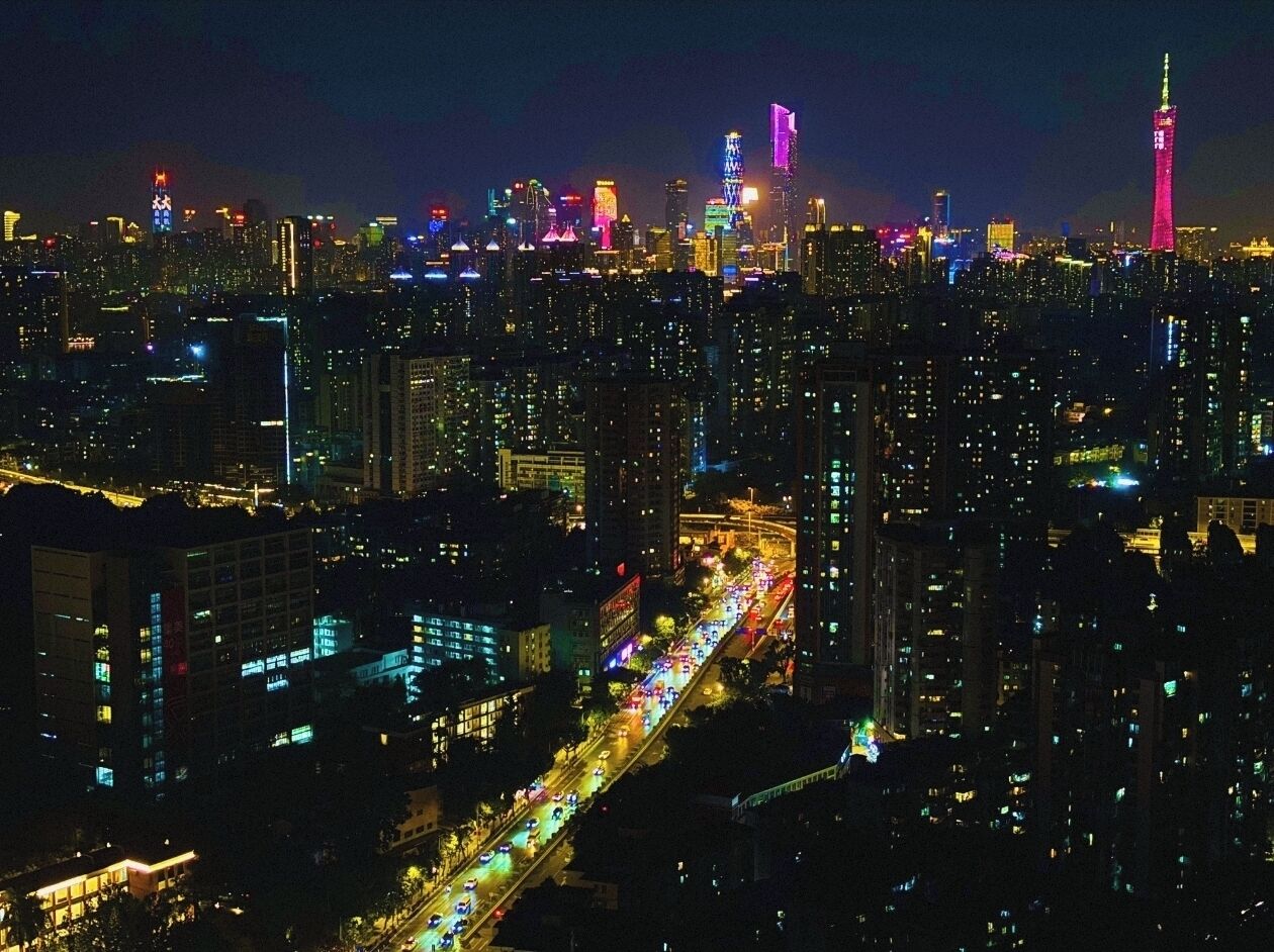 A nighttime cityscape with illuminated buildings and a busy road.