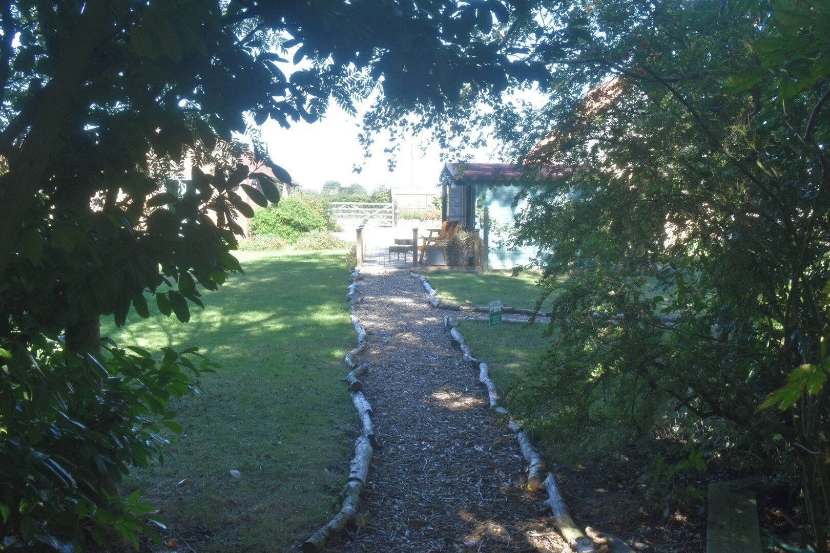 A pathway leading to a building with a red roof, surrounded by greenery and trees.