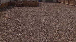 A gravel-covered outdoor area with a wooden deck, a small shed, and a mobile home. - Lapwing Lodge, Howdales (Lincolnshire)