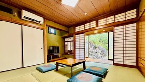 A traditional Japanese room with tatami flooring, a low wooden table, cushions, sliding doors, and a television. - Fumiko-no-tei Hanare 1 minute walk to the sea 17 - 34 people OK 4 bedrooms 2 toilets (西牟婁郡白浜町)