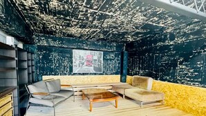 A room with a black and yellow wall, a wooden floor, a sofa, a chair, and a coffee table. - Fumiko-no-tei Hanare 1 minute walk to the sea 17 - 34 people OK 4 bedrooms 2 toilets (西牟婁郡白浜町)