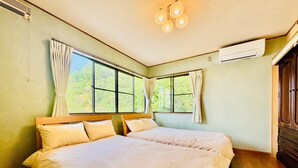 A bedroom with two beds, large windows, an air conditioning unit, and a wooden wardrobe. - Fumiko-no-tei Hanare 1 minute walk to the sea 17 - 34 people OK 4 bedrooms 2 toilets (西牟婁郡白浜町)