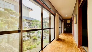 A corridor with large glass windows, wooden flooring, and a view of a garden and traditional building. - Fumiko-no-tei Hanare 1 minute walk to the sea 17 - 34 people OK 4 bedrooms 2 toilets (西牟婁郡白浜町)
