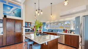 A modern kitchen with a large island, bar stools, and a view of the ocean through large windows. - Casa De La Bandera//Private villa, amazing views! (Rincon)
