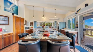 A dining area with a large table set for six, surrounded by black chairs. There are hanging pendant lights above the table. - Casa De La Bandera//Private villa, amazing views! (Rincon)