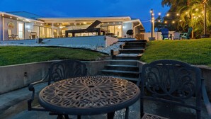 Una casa moderna con patio, mobiliario exterior y una escalera que lleva a la entrada.