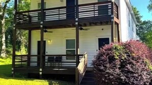 A two-story house with a balcony on the upper floor, a covered porch on the lower floor, and a small garden area with bushes. - The Lair at Georgia Tech and Mercedes-Benz Stadium (Atlanta)