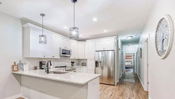 A modern kitchen with white cabinets, stainless steel appliances, and a central island. - The Lair at Georgia Tech and Mercedes-Benz Stadium (Atlanta)