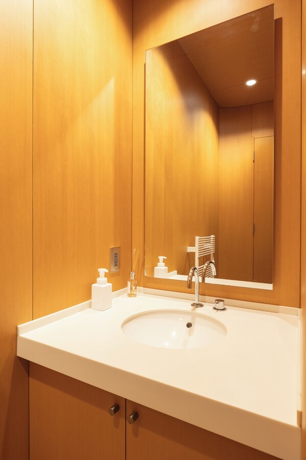 A bathroom with wooden walls, a white sink, a mirror, and a towel rack.