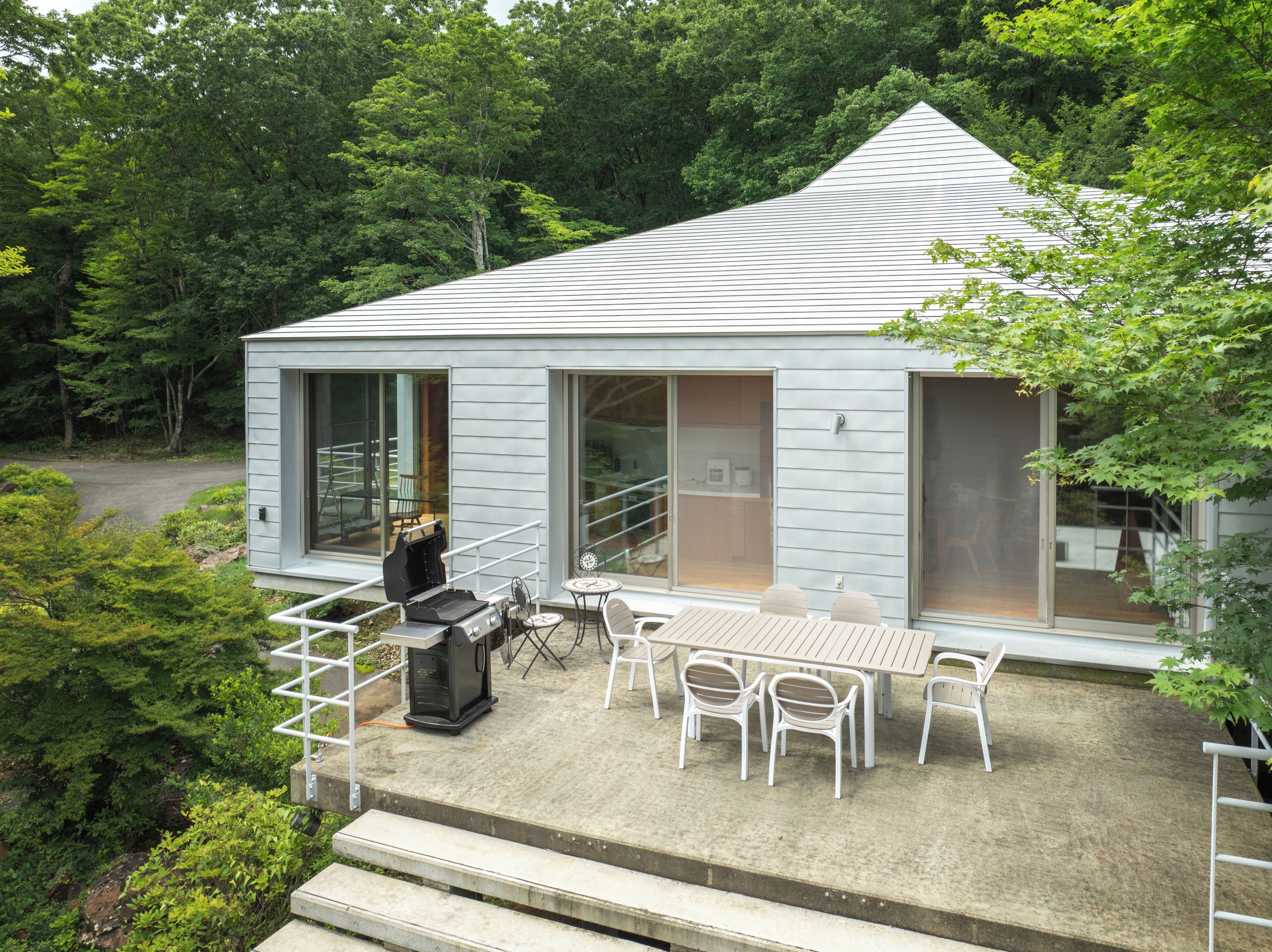 A modern house with a patio, outdoor grill, and seating area.