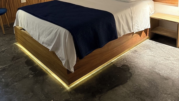 A modern bedroom with a wooden bed frame, white bedding, and a dark blue throw blanket. - Hostetia 7 in the heart of the historic center of Zacatecas (Zacatecas)