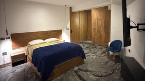 A modern bedroom with a bed, a chair, a TV, and a wooden wardrobe. - Hostetia 7 in the heart of the historic center of Zacatecas (Zacatecas)