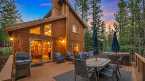 Una cabaña de madera con terraza, mobiliario exterior y un jacuzzi.