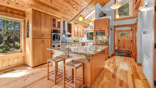 Una cocina amplia con armarios de madera, una isla grande con taburetes e iluminación colgante.
