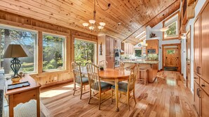 Interior de madera con comedor, cocina y ventanas amplias.