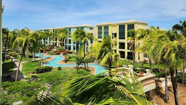 A resort with multiple buildings, a swimming pool, and palm trees.